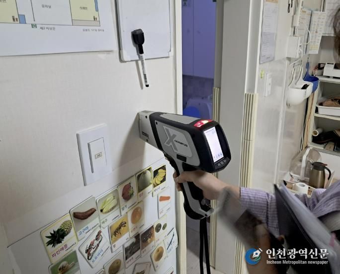 구청 관계자가 어린이집 실내 벽에 사용된 도료의 중금속 함량을 측정하고 있다