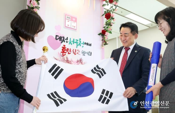 서철모 서구청장이 구청 민원실을 방문한 국제결혼 부부에게 태극기를 전하고 있다