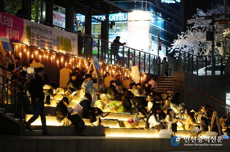 야간 조명이 켜진 성북천 수변활력거점에서 시 민들이 여유롭게 공연과 휴식을 즐기고 있다.